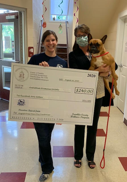 Check presented to Antietam Animal Shelter, woman holding check next to woman holding a 30 pound bulldog
