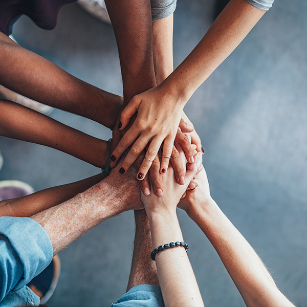 Close up top view of young people putting their hands together. Friends with stack of hands showing unity and teamwork.