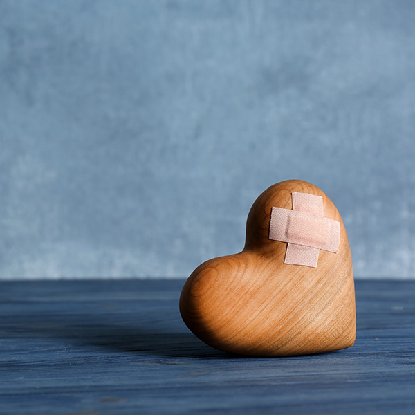 Wooden heart with adhesive plasters on table.