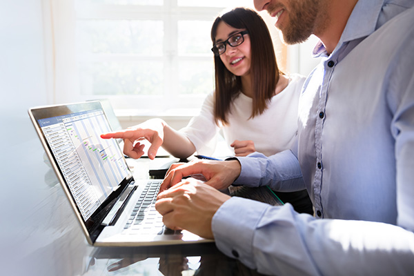 Woman looks on as a coworker uses a laptop