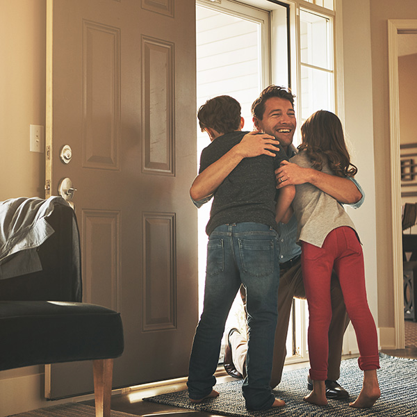 Home, love and a father hugging his kids after arriving through the front door after work during the day.