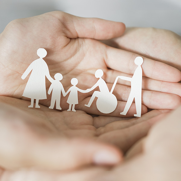 A paper cutoutof a family being held by small hands.