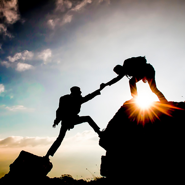 Someone helping another person up a mountain