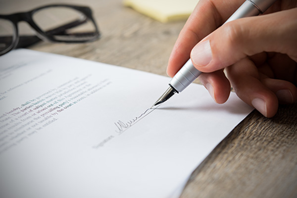 A close up of a hand signing a document.