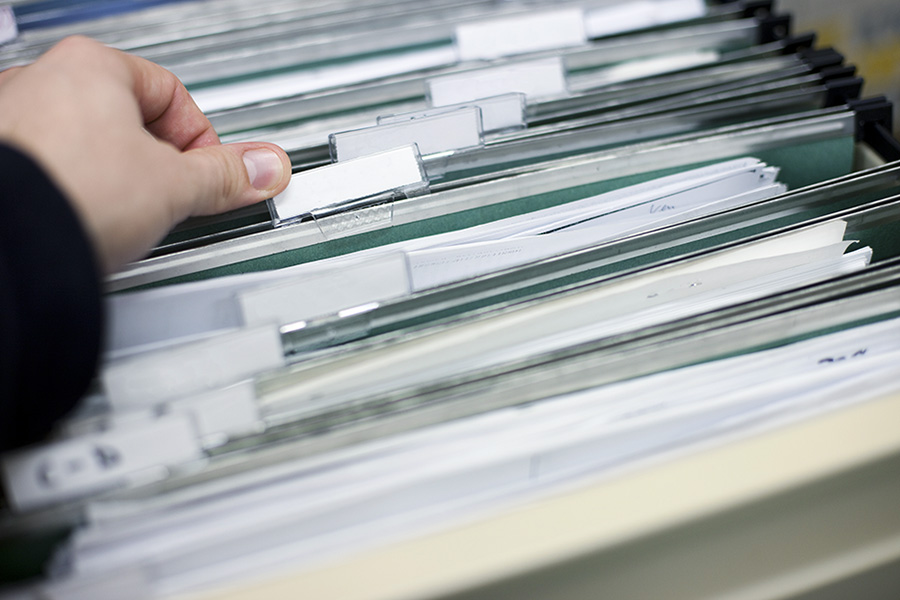 Person thumbing through a filing cabinet and files.