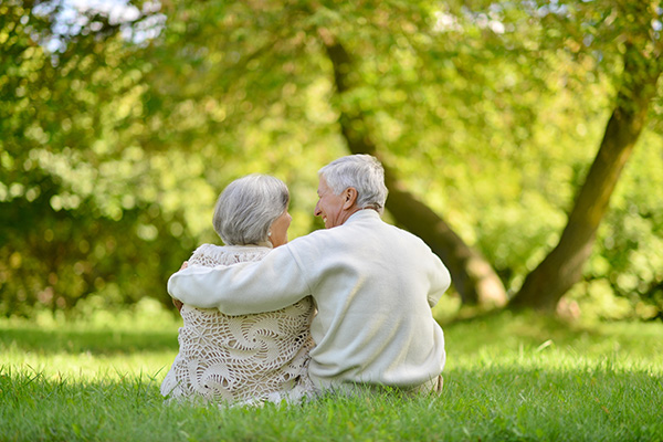 Elderly couple smiling at looking at each other in a beautiful grass field.