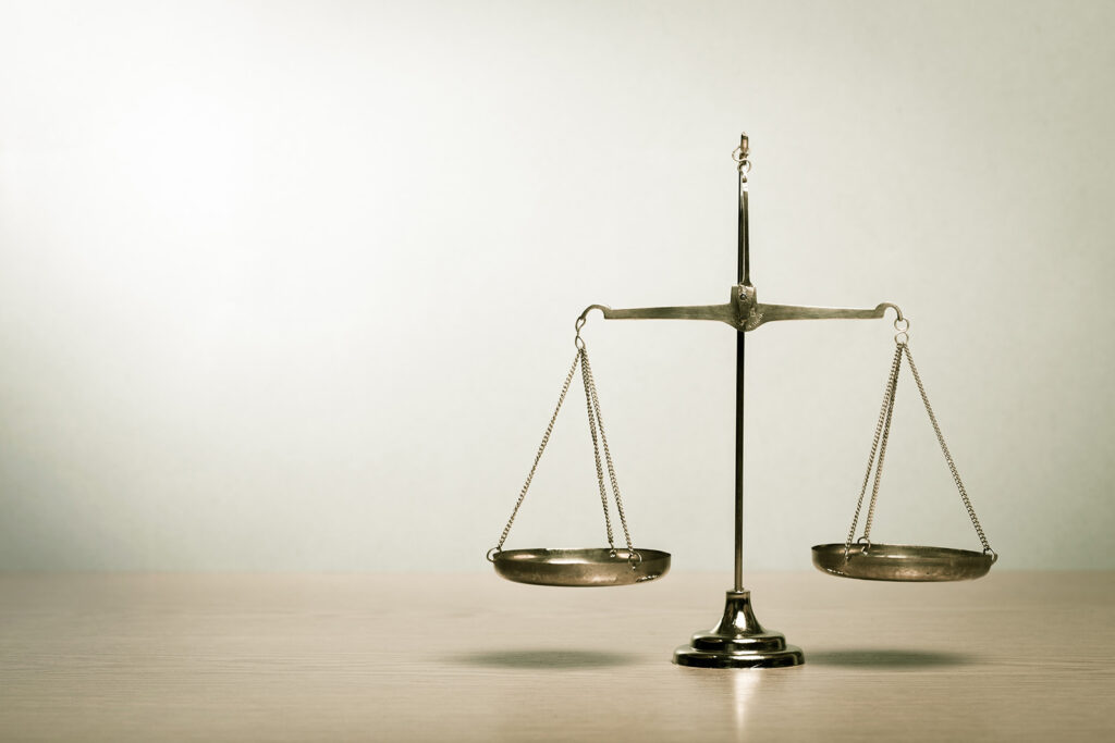 The scales of justice on a table against a beige background.