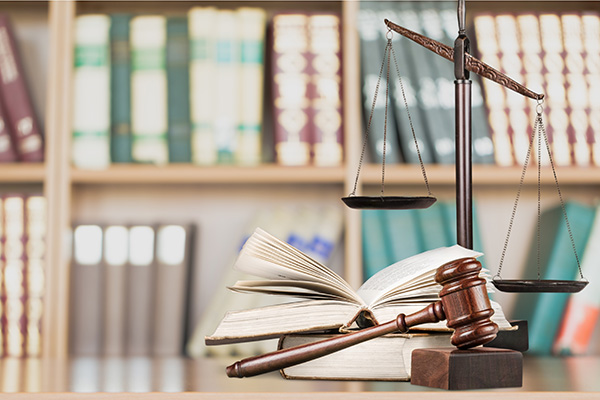 Scales of justice on top of law books in a library.