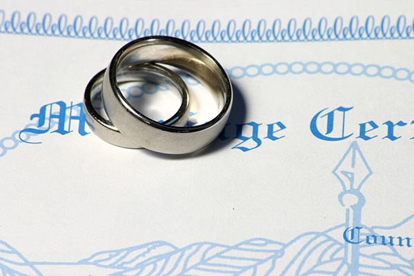 Two wedding bands over a marriage certificate.