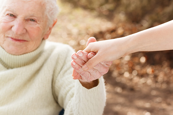 A younger woman holding the hand of an older woman.