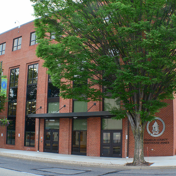 The exterior of the courthouse annex building, and a tall tree.