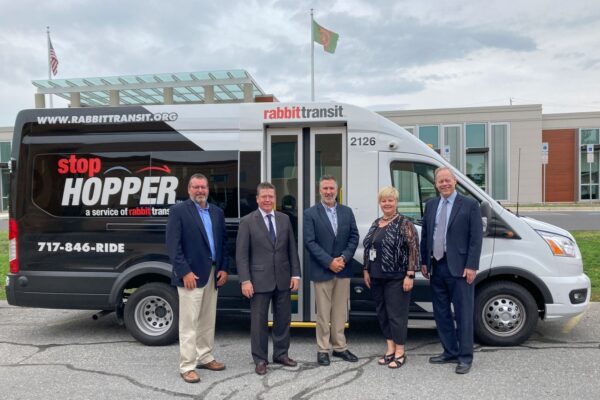 Five people stand in front of a Rabbit Transit van with 