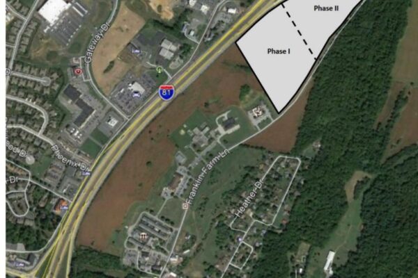 Aerial view of a highway interchange with marked areas labeled Phase I and Phase II adjacent to a wooded region and residential area in Stoufferstown.