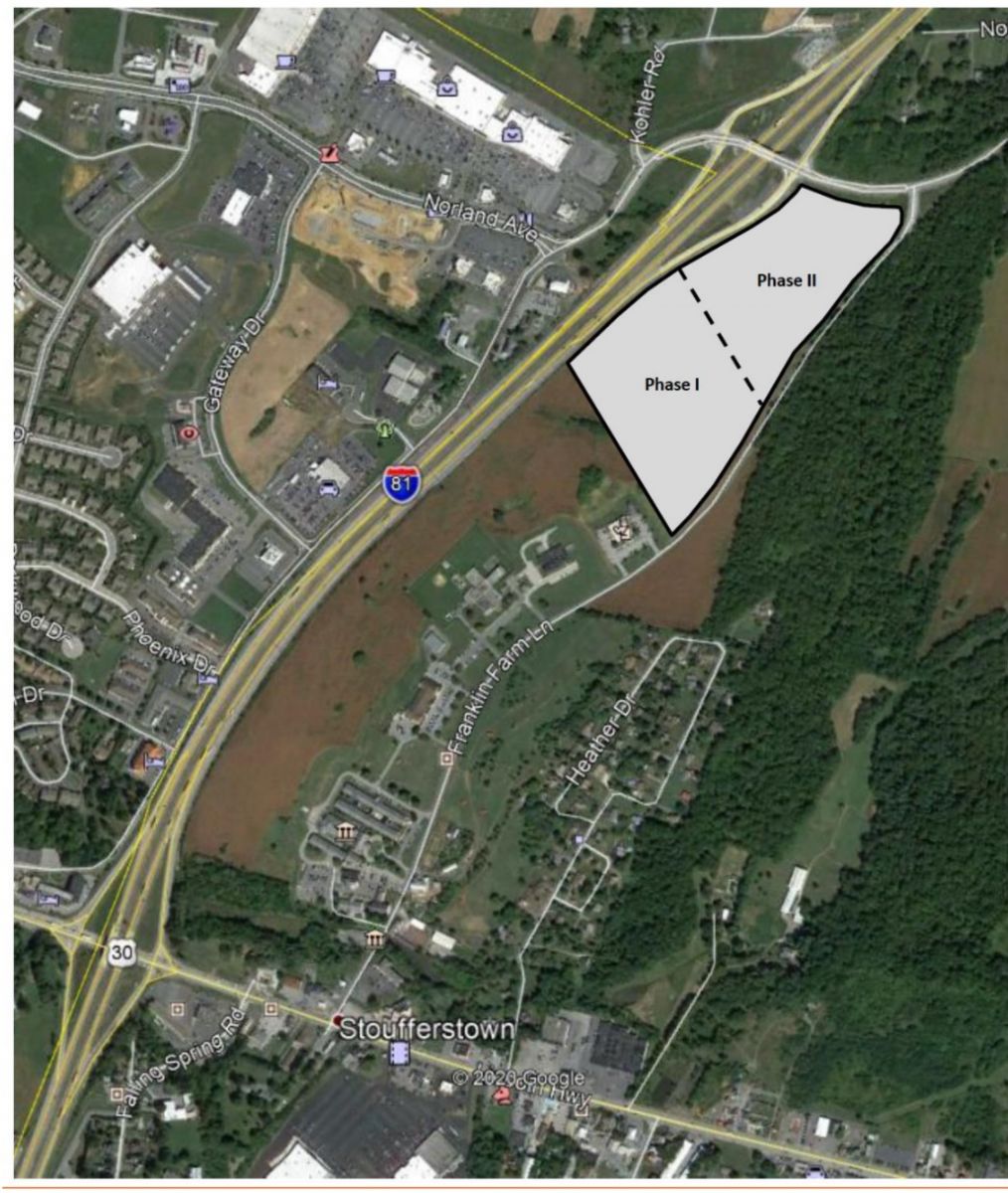 Aerial view of a highway interchange with marked areas labeled Phase I and Phase II adjacent to a wooded region and residential area in Stoufferstown.